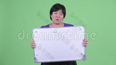 快乐年轻、体重超重的亚洲女人拿着白板说话