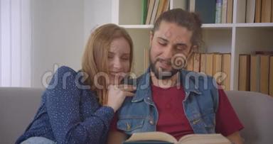 <strong>肖像</strong>镜头中年轻的白种人男女朋友坐在沙发上快乐地在家<strong>看书</strong>。