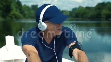 一个头发花白、戴着白耳机、戴着蓝帽子、穿着t恤、戴着眼镜的男子在白船上划桨