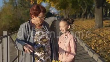 小孙女带着一束秋天的黄叶，跑到公园里他心爱的祖母身边，拥抱她。