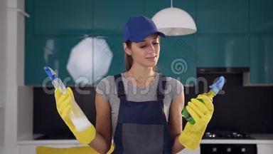 年轻的微笑妇女从清洁服务，比较两个喷雾清洁剂在她的<strong>手中</strong>的菜肴