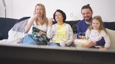 幸福的一家人坐在沙发上，一起看电视，一起吃爆米花。