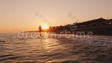 日落时一个少年绕着冲浪线奔跑的剪影