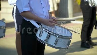 街头表演的鼓手男孩的节日游行服装在城市街头。 男孩`的手鼓手是特写的