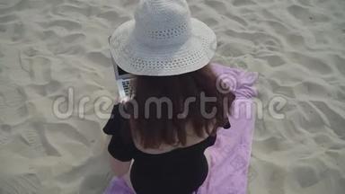 在海滩上，年轻女子戴着白色帽子，带着笔记本电脑工作。 自由职业概念。 忙碌的女人