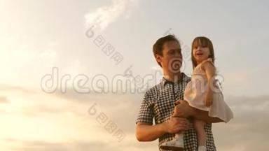 小女儿和爸爸正在一片成熟的麦子里玩耍.. 孩子在父亲的怀里。 小男孩和爸爸