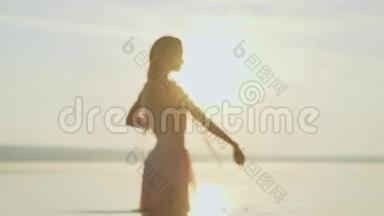 黎明阳光下的女孩在怀特跳舞。 日落海滩上的年轻<strong>苗</strong>条美丽的女人，嬉戏，跳舞