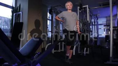 一位做膝上举的年长妇女站起来练习关节体操。 复制空间。前视。滑翔摄像机镜头