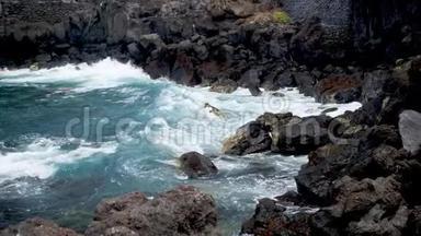 海洋巨浪在海岸的黑色悬崖和岩石上翻滚和破碎的4K慢动作视频