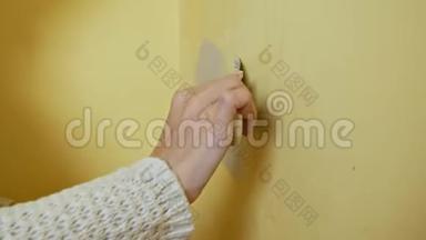 女孩在画之前把房间里的黄墙吐出来。 DIY修理。 把关节绑起来。 年轻女子穿上