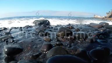 特写慢动作视频：海浪在沙滩上翻滚的黑色卵石