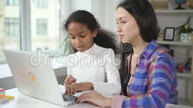 年轻的非洲女孩同意白种人的导师在网上学习使用新的现代技术笔记本电脑。