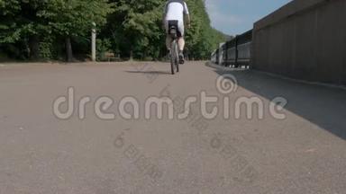 一个运动员，骑上自行车，毫无重点地从摄像机旁开。