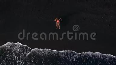 漫画视频-一个穿着<strong>红色</strong>泳衣的女人在黑色的火山海滩上<strong>爬行</strong>到水中，拍摄一个<strong>红色</strong>泳衣的顶部景色