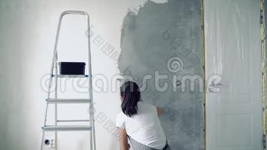 女工人在公寓或房子里用铲子粉刷墙壁。 把注意力集中在手上