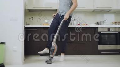 <strong>快</strong>乐男人在厨房打扫地板。 带着吸尘器跳起<strong>来的快</strong>乐男人