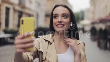 一个戴着耳机的漂亮微笑的女孩，用视频通话，保持电话垂直通话