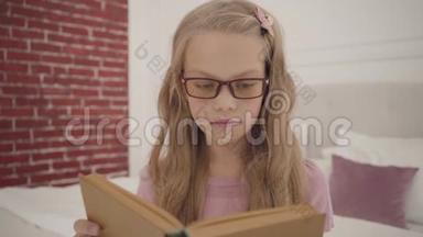 一个戴眼镜的年轻聪明的十几岁女孩在家<strong>看书</strong>的<strong>肖像</strong>。 聪明的白人金发女生