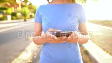日落时分，一个穿着智能手机<strong>的</strong>蓝色裙子<strong>的</strong>女人在棕榈街散步