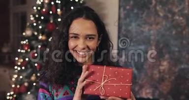 美丽幸福的女人手里拿着漂亮的礼品盒的肖像，展示在舒适的家中的镜头