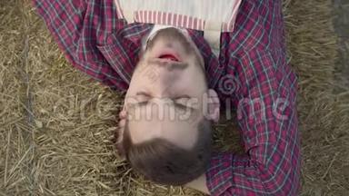 年轻人躺在干草上吃新鲜苹果的特写镜头。 农夫下班后休息。 农村生活方式