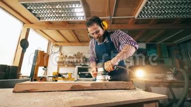 木板是由一个男木匠打磨的. 从事木工工作的工匠。