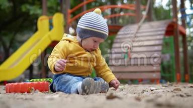 小可爱的<strong>男孩</strong>，是坐在沙滩背景上玩耍的操场.. 穿着黄色<strong>毛衣</strong>和帽子的秋天
