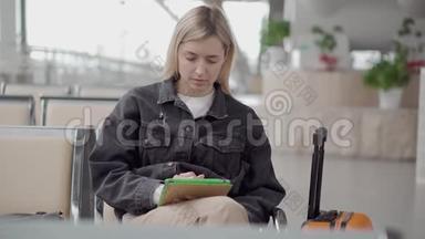 一个人坐在车站<strong>候车厅</strong>里，女人正在用平板电脑查看电子邮件