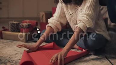 年轻美丽的穆拉托女孩坐在装饰的圣诞树下，准备礼物，用纸卷