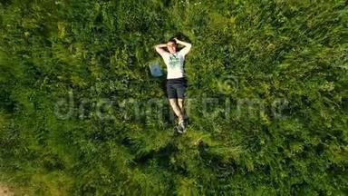 一个自由职业者用笔记本电脑躺在草地上。 空中无人机镜头俯视。