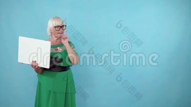 一位体贴的老妇人手里拿着笔记本电脑，找到了解决<strong>办法</strong>，站在蓝色背景的复印空间上