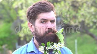 盛开的花园里有一个长着大胡子的人。 夏天的男人和有趣的时刻。 花里长胡须。 有趣的胡子画像。