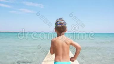 快乐的小男孩跑进大海，享受暑假。 清澈的蓝色水，金色的沙滩。