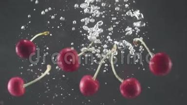 掉落的新鲜樱桃和樱桃溅入水中的黑色背景。 特写镜头。 加速录像。