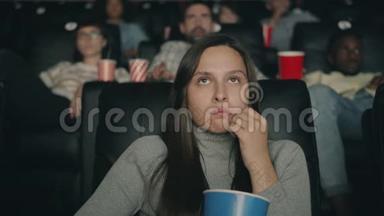 恐怖的女人在电影院看恐怖电影，吃着爆米花闭上眼睛