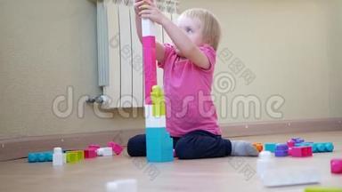 孩子搭建一座彩色积木塔.. 可爱的小女孩在玩五颜六色的建筑塑料块上