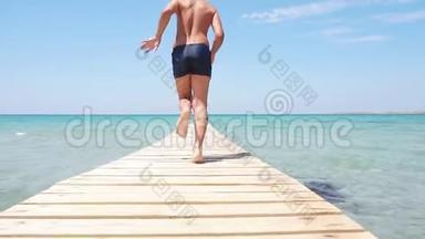 暑假快乐。 青少年跑进大海，享受暑假。 清澈的蓝色水，金色的沙滩。