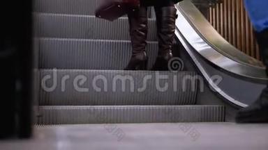 人们的腿在商场的自动扶梯电梯上移动。 购物中心`扶梯上的购物者脚