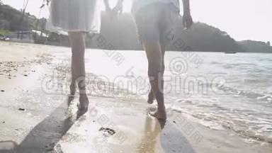 夏天，妈妈和女儿一起在阳光下快乐地在海滩上散步和牵手。