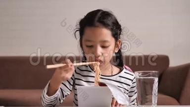 亚洲小女孩用<strong>筷子</strong>吃着美味的<strong>方便面</strong>，幸福地选择焦点，浅野