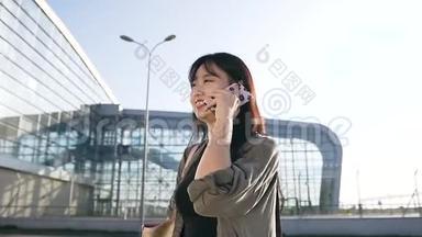 美丽的肖像吸引人的年轻的亚洲黑发，长发，在机场大楼附近的电话交谈