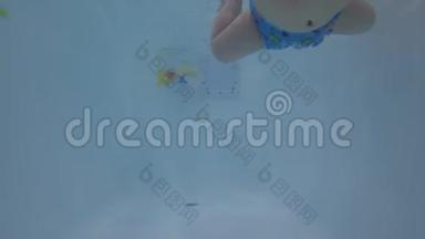 快乐宝宝学习在游泳池游泳.. 宝贝学习游泳。 未编辑的水下录像。