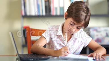 小女孩用笔记本电脑和笔记本做作业。