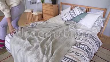 一个穿着<strong>家居</strong>服的女人下床，用灰色格子铺床。 罗夫斯堪的纳维亚<strong>风</strong>格公寓