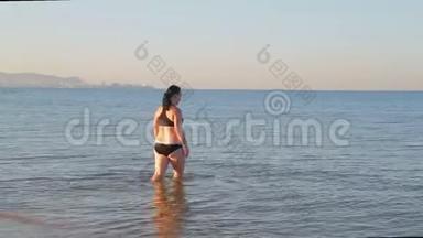 一个穿着运动泳衣的黑发<strong>女人在做瑜伽</strong>后去海里游泳。