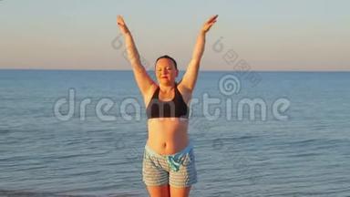 一位身穿运动服的黑发女子清晨在海滨做体操