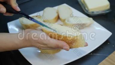 女人用刀把黄油涂在面包上。 厨师在罐头上涂黄油。 刀尖在白面包上撒玛格丽。 H.