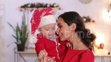 一位<strong>母亲抱</strong>着一个戴着圣诞帽的小<strong>孩子</strong>的特写镜头。 圣诞节。