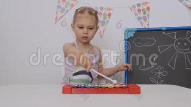 一个小女孩坐在孩子们房间`桌子旁玩<strong>木琴</strong>