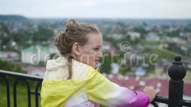 少年女孩在公园的<strong>观景台</strong>上跳到围栏附近，<strong>俯瞰</strong>城市。